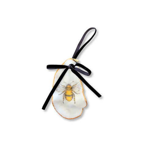 Slim decoupage oyster shell ornament with a centered bumblebee, gilded rim, and black velvet ribbon by Melissa Fouts.