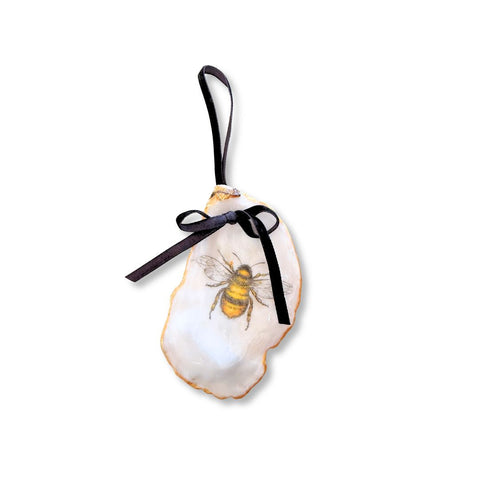 Decoupage oyster shell ornament with a bumblebee, gilded rim, and black velvet ribbon by Melissa Fouts.