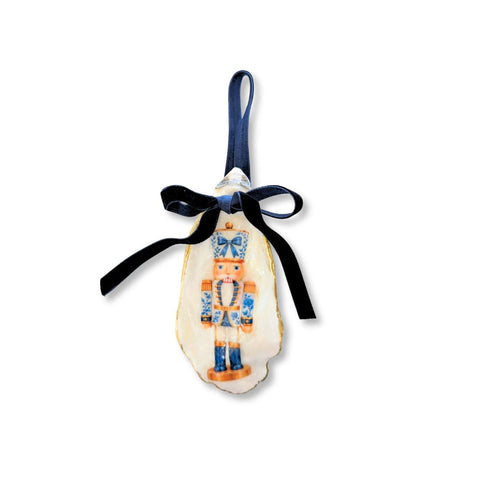 Decoupage oyster shell ornament with a blue-and-white chinoiserie nutcracker on a tall shell, gilded rim, and navy velvet ribbon by Melissa Fouts.