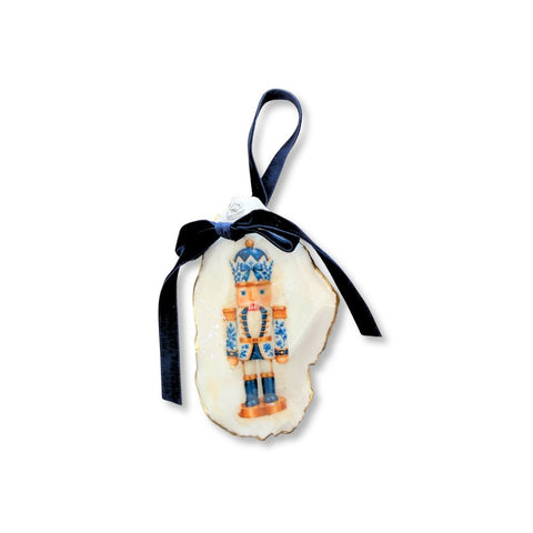 Decoupage oyster shell ornament with a blue-and-white chinoiserie nutcracker on a wide shell, gilded rim, and navy velvet ribbon by Melissa Fouts.