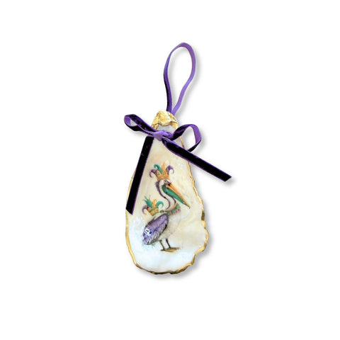 Decoupage oyster shell ornament with a pelican in a Mardi Gras jester cap, gilded rim, and purple velvet ribbon by Melissa Fouts.