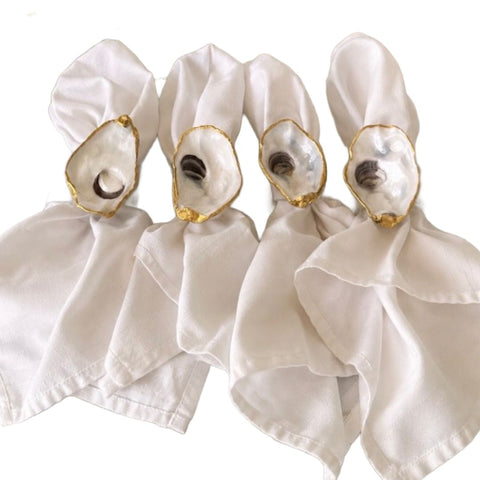 Set of four gilded oyster shell napkin rings with white napkins by Melissa Fouts