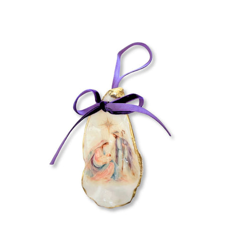 Decoupage oyster shell ornament with a pastel nativity scene under a star, gilded rim, and purple ribbon by Melissa Fouts.